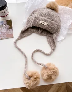 Detail of wool knit balaclava hat with soft pom-poms and minimalist BONOGEED label