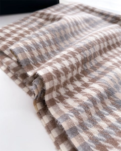 Close-up of soft houndstooth scarf texture with brown, beige and grey woven fibers