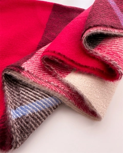 Detailed texture of red and beige checkered cashmere-feel scarf with soft fringe edges