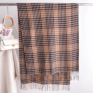 Detailed view of the houndstooth pattern and soft fringe tassels on a winter shawl scarf