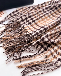 Detailed close-up of brown houndstooth pattern and fringe tassels on winter scarf