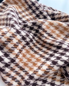 Detailed close-up of soft houndstooth cashmere shawl with brown and beige woven textures