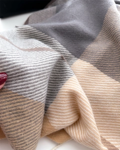 Close-up of thick plaid scarf featuring soft twill weave in grey and beige
