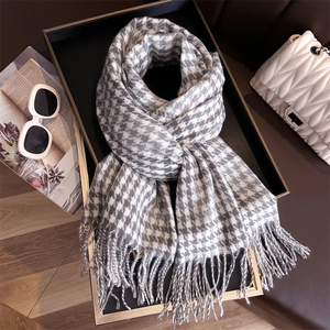 Detailed view of grey houndstooth scarf texture with long fringes and autumn styling