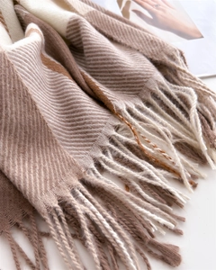 Detail of classic brown checkered knit scarf featuring soft fringe and twill texture