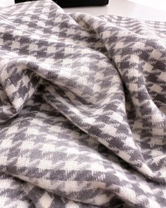 Detailed view of grey and white houndstooth fabric with soft woven texture and fringes