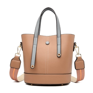 Brown bucket handbag with grey handles and striped shoulder strap on white background