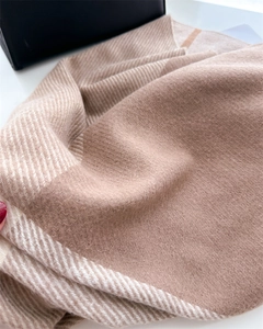 Detail of herringbone knit texture on beige cashmere-like scarf with striped edges