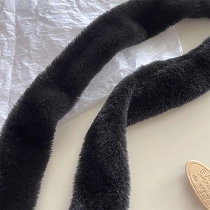 Detailed macro view of black faux cashmere scarf texture and elegant gold brand plaque