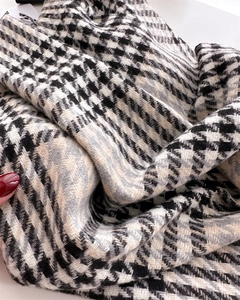 Detail shot of soft cashmere-like plaid scarf featuring classic houndstooth pattern and fringe