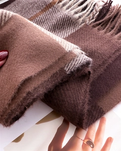Close-up of soft cashmere-like plaid scarf featuring classic brown tassels and thick texture