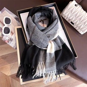 Detail of plaid scarf featuring black and grey tassels next to fashion accessories
