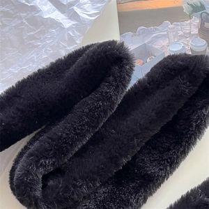 Close-up of fluffy black faux fur scarf texture with a warm winter outdoor aesthetic