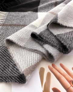 Detail of soft cashmere-like scarf showing classic plaid pattern and fringe texture