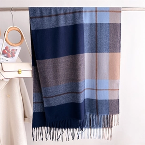Close-up of thick plaid cashmere-like scarf featuring navy and blue fringe details