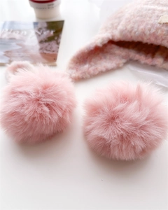 Detail of soft pink faux fur pom-pom on matching knitted wool balaclava winter hat