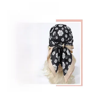 Macro detail of silk scarf featuring black and white camellia pattern with beige edges