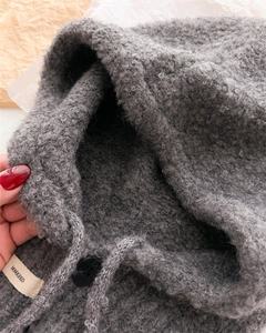 Dettaglio di passamontagna grigio con coulisse, bottone nero e trama di lana