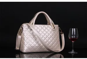 Detailed close-up of beige quilted faux leather handbag with golden metal hardware