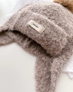 Detail of light brown knit balaclava with pompom and BONOGEED label for winter