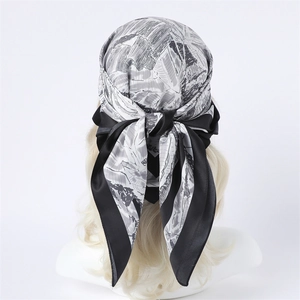 Vue détaillée d'un foulard en soie noir et blanc porté élégamment comme un bandeau chic