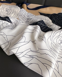 Detail of silk twill scarf showing black and white rose patterns and beige stitching