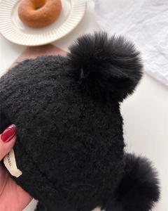 Detail of black faux lamb wool balaclava with soft knit texture and fluffy pom-pom