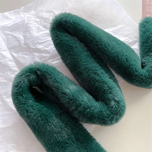 Close-up of soft dark green faux fur scarf showing thick plush texture and luxury sheen