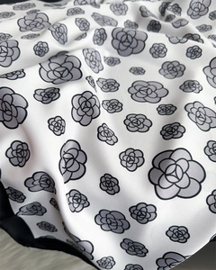 Macro detail of white floral silk scarf showing grey camellia prints and soft fabric texture