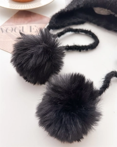 Detail of soft black faux fur pom-poms on a knitted winter balaclava hood