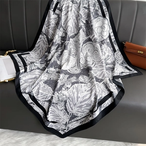 Détail de l'élégant foulard en soie à motif floral noir et blanc drapé sur un canapé