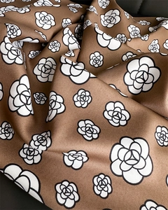 Detailed view of brown satin scarf fabric with camellia floral print and twill texture