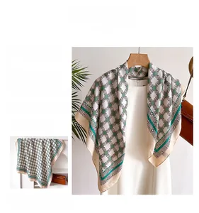 Dettaglio di elegante foulard in seta a motivi geometrici beige e verdi con borsa