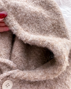 Dettaglio del passamontagna in lana con trama bouclé, coulisse e bottone beige