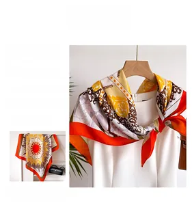 Detail eines eleganten Seiden-Halstuchs mit orangefarbenem Barockmuster und Fischgrät