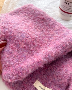 Dettaglio della trama in maglia bouclé rosa viola e dell'etichetta tessuta sul berretto