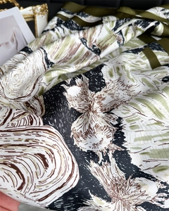 Détail macro du foulard en soie montrant la texture florale et les bords satinés olive