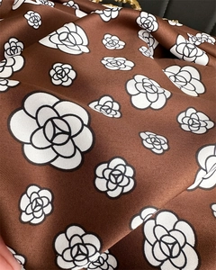 Detailed view of the brown satin scarf featuring elegant camellia prints and silky twill texture