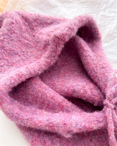 Dettaglio ravvicinato del passamontagna in lana viola-rosa con trama e lacci regolabili