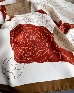 Detailed view of white twill silk scarf with red camellia floral print and brown border