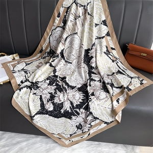 Carré en soie à imprimé fleurs posé sur un canapé en cuir avec un sac à main chic