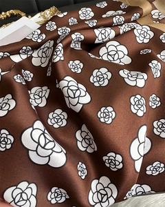 Detailed close-up showing the twill texture and white camellia print on a silk-like scarf