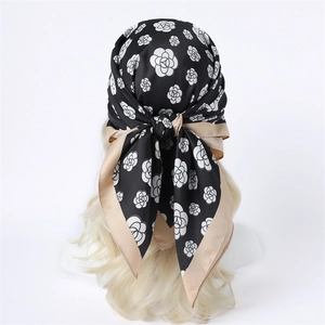 Detailed view of silk square scarf with camellia print worn as elegant headscarf