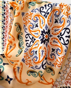 Detailed macro view of orange and navy paisley printed silk scarf with floral patterns