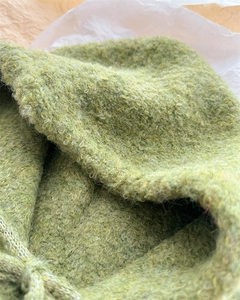Macro del tessuto a maglia bouclé verde prato con dettagli morbidi del filato riccio