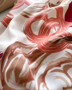 Macro detail of the herringbone twill weave texture on a caramel floral silk scarf