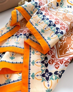 Close-up of bohemian silk scarf featuring intricate geometric prints and orange borders