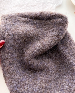 Dettaglio ravvicinato della lana bouclé viola caffè e della trama morbida a maglia