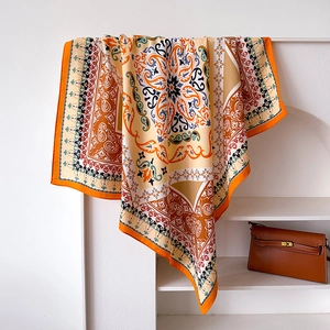 Detail of elegant silk scarf with paisley pattern draped over a minimalist stand