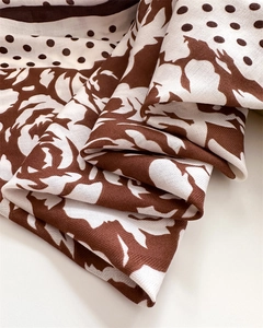 Macro shot of silk scarf detailing retro rose patterns and dotted herringbone texture